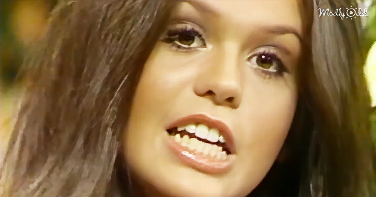 A person with long dark hair and a slightly open mouth is shown in a close-up shot.