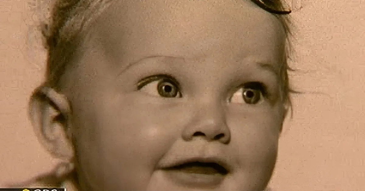 A sepia-toned image of a young child with wide eyes and a curious expression.