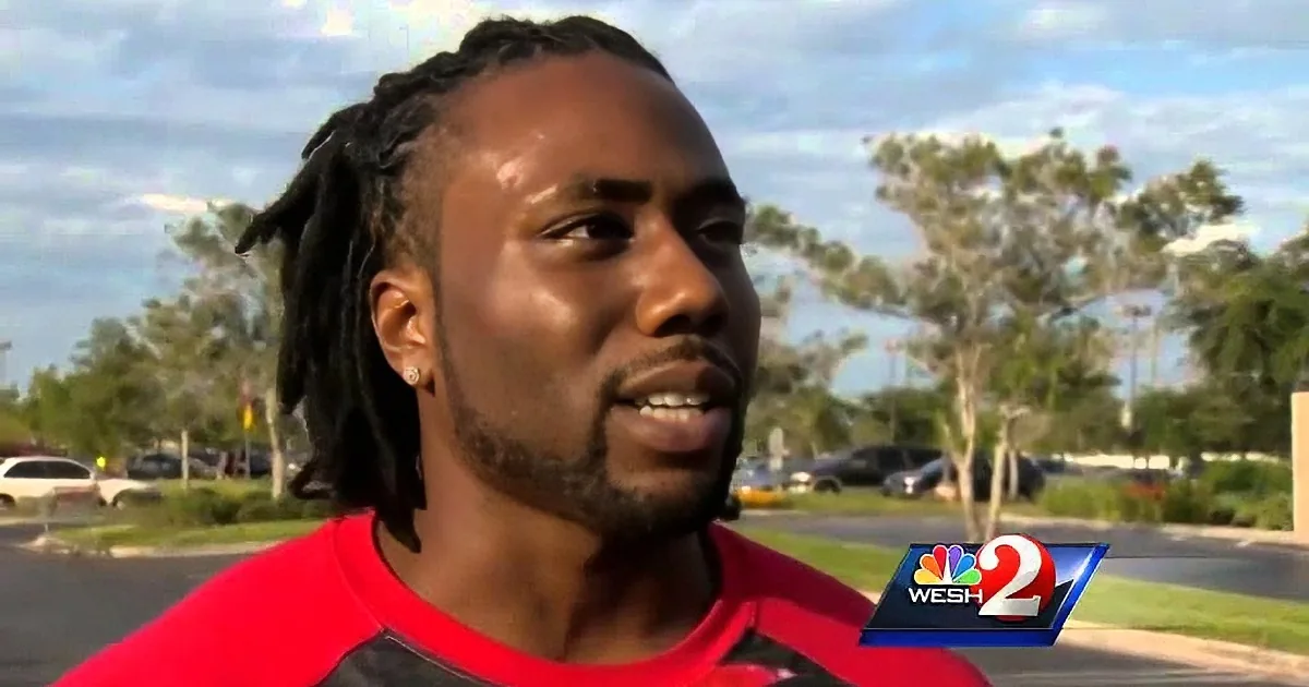 A man with dreadlocks and a red shirt is being interviewed outdoors, with a NBC WESH 2 logo in the corner.