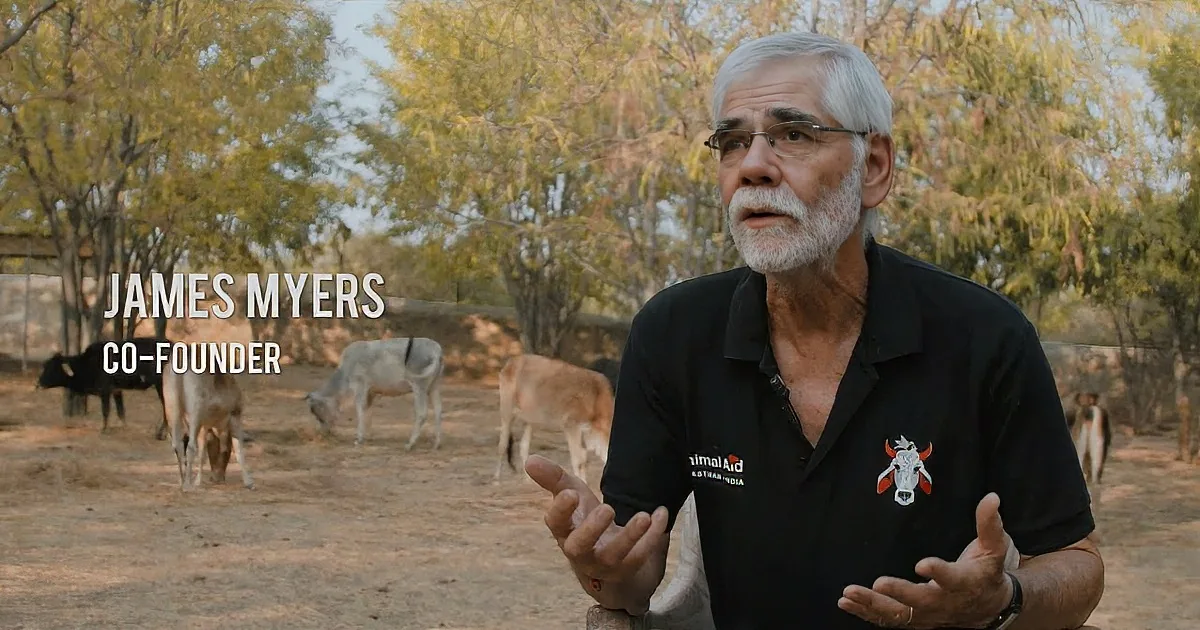 James Myers, co-founder, gestures while speaking in front of a herd of animals in a natural setting.