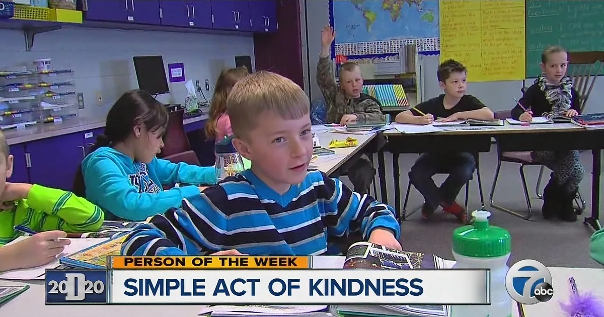 A young boy in a striped shirt sits at a desk in a classroom, surrounded by classmates, with a water bottle and a "Person...