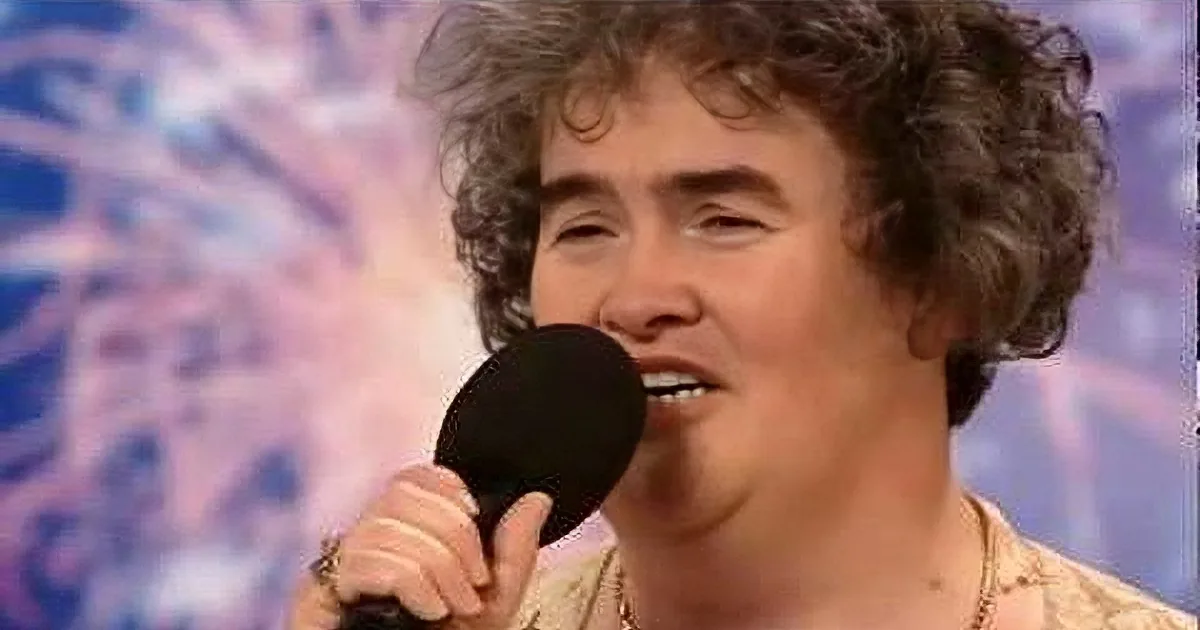 A person with curly hair holds a microphone, singing against a vibrant background.