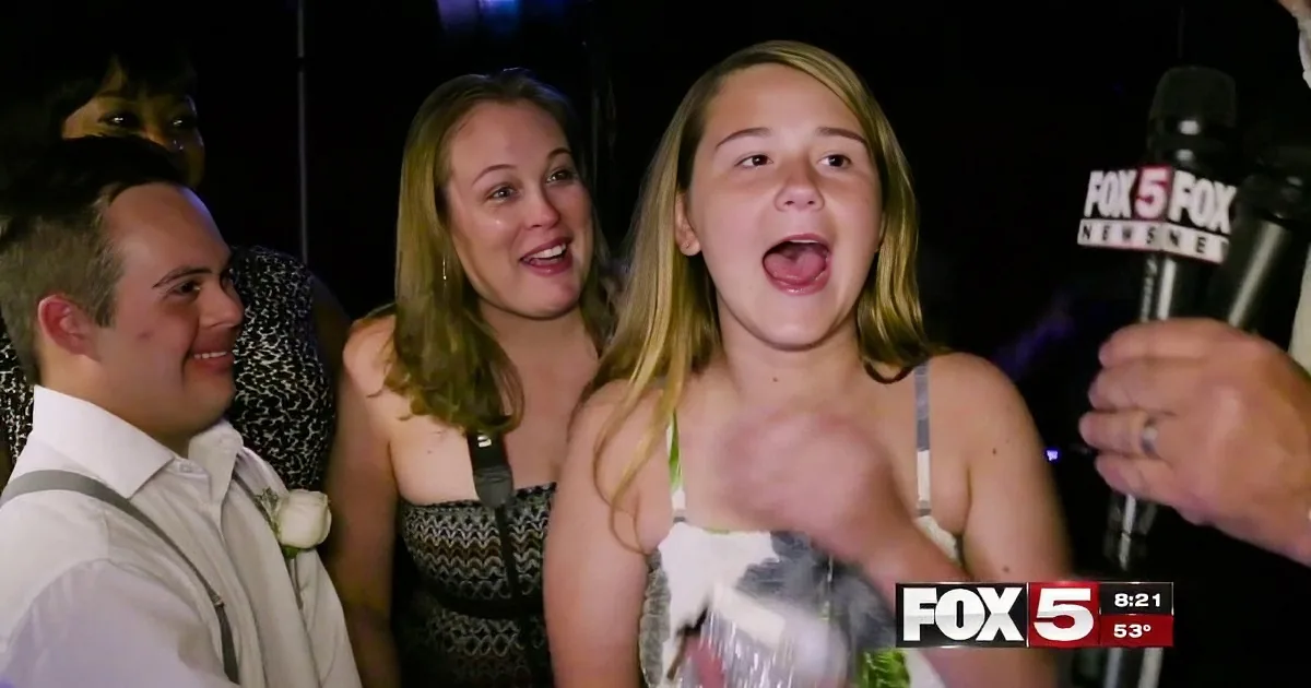 A young woman with long blonde hair is being interviewed by a reporter at a nighttime event.