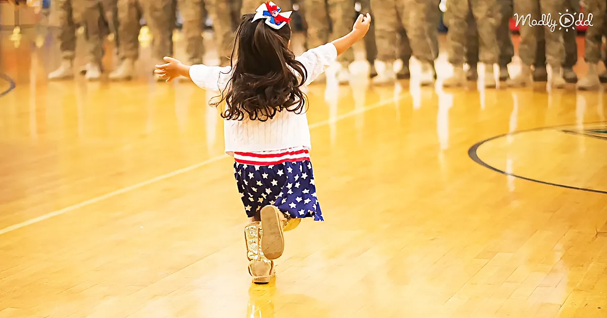 A child in a patriotic outfit runs joyfully on a polished wooden floor, with soldiers in the background.