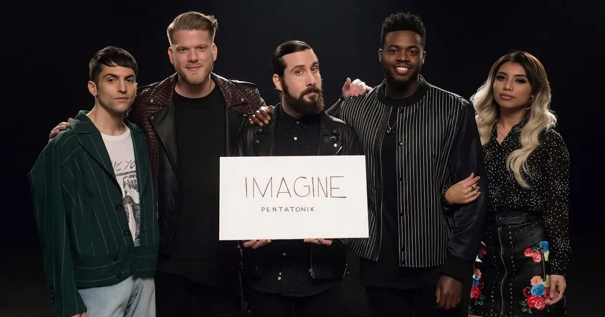 Five individuals stand together, holding a sign that reads "Imagine Pentatonix," dressed in stylish attire against a dark...
