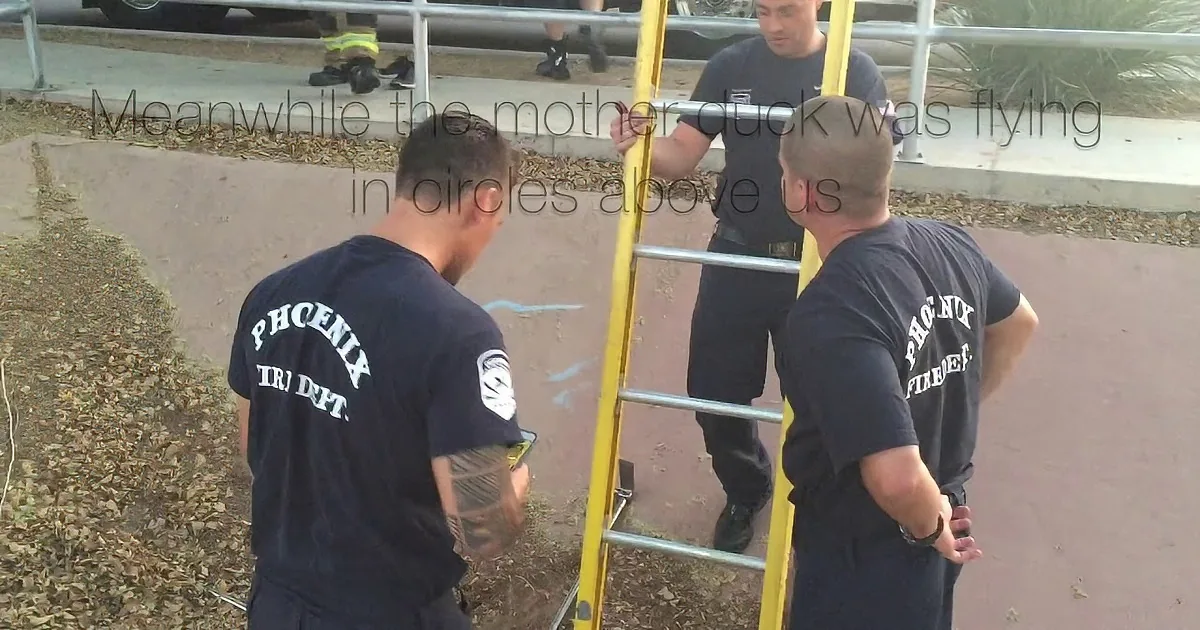Four individuals in dark uniforms work together to lift a heavy object from a grate.