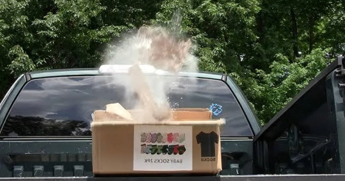 A steam or smoke is billowing from a cardboard box on the back of a truck.