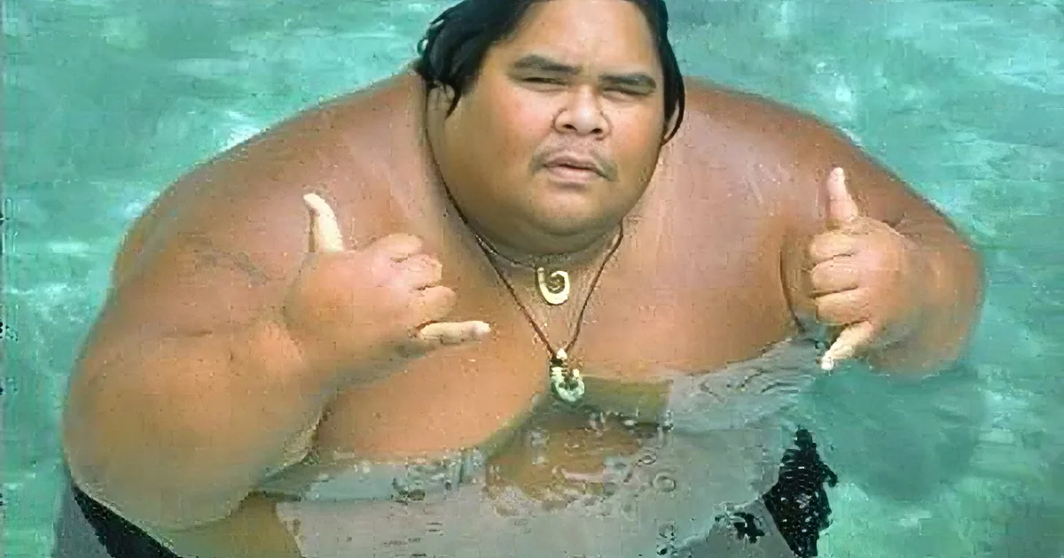A person with a large build gives a thumbs-up in a swimming pool.