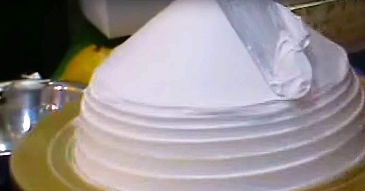 A close-up of a white, swirled dessert on a yellow plate, possibly a meringue or cake.