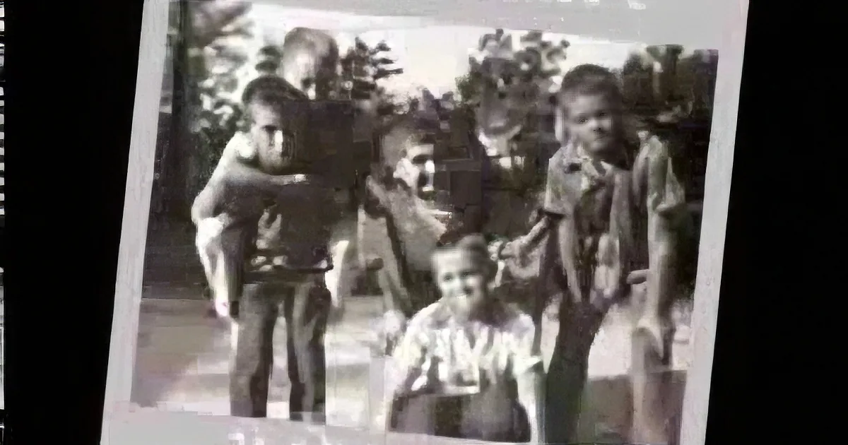 A group of people, possibly soldiers, are gathered outdoors, some standing and some sitting, in a black-and-white photo.