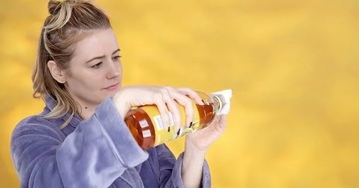 A woman in a blue top pours a bottle of liquid, possibly maple syrup, with a yellow background.