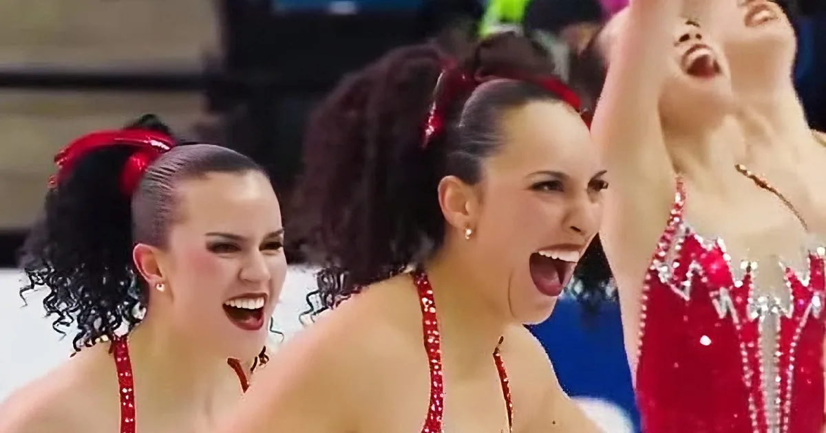 A woman in a red and white outfit with a red headband is smiling and raising her arm.