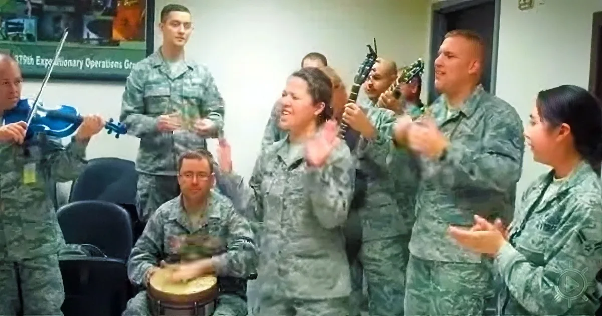 A group of soldiers in uniform is playing musical instruments and clapping in a room.