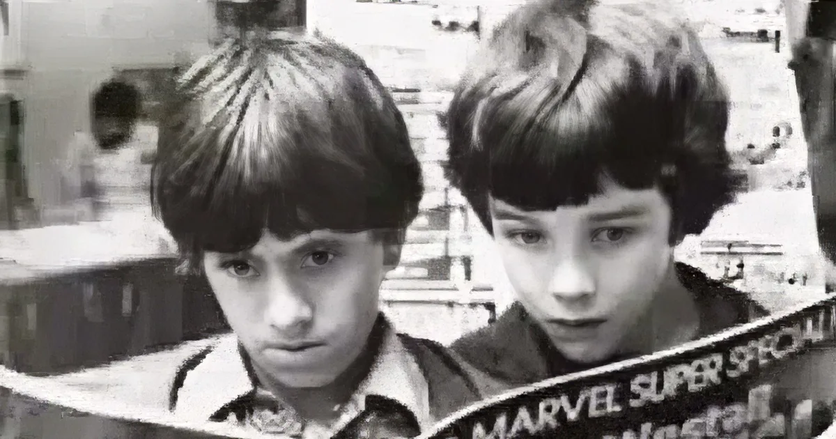 A young boy with short hair is prominently featured, holding a Marvel comic book.