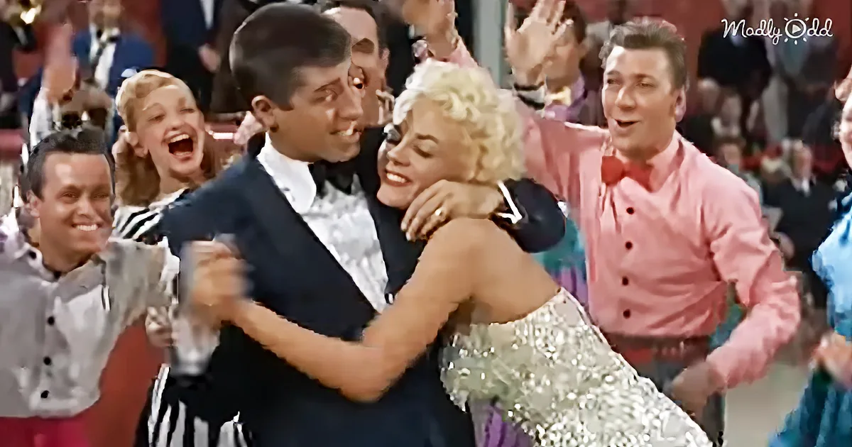 A couple dances joyfully in a lively crowd, surrounded by cheering onlookers.