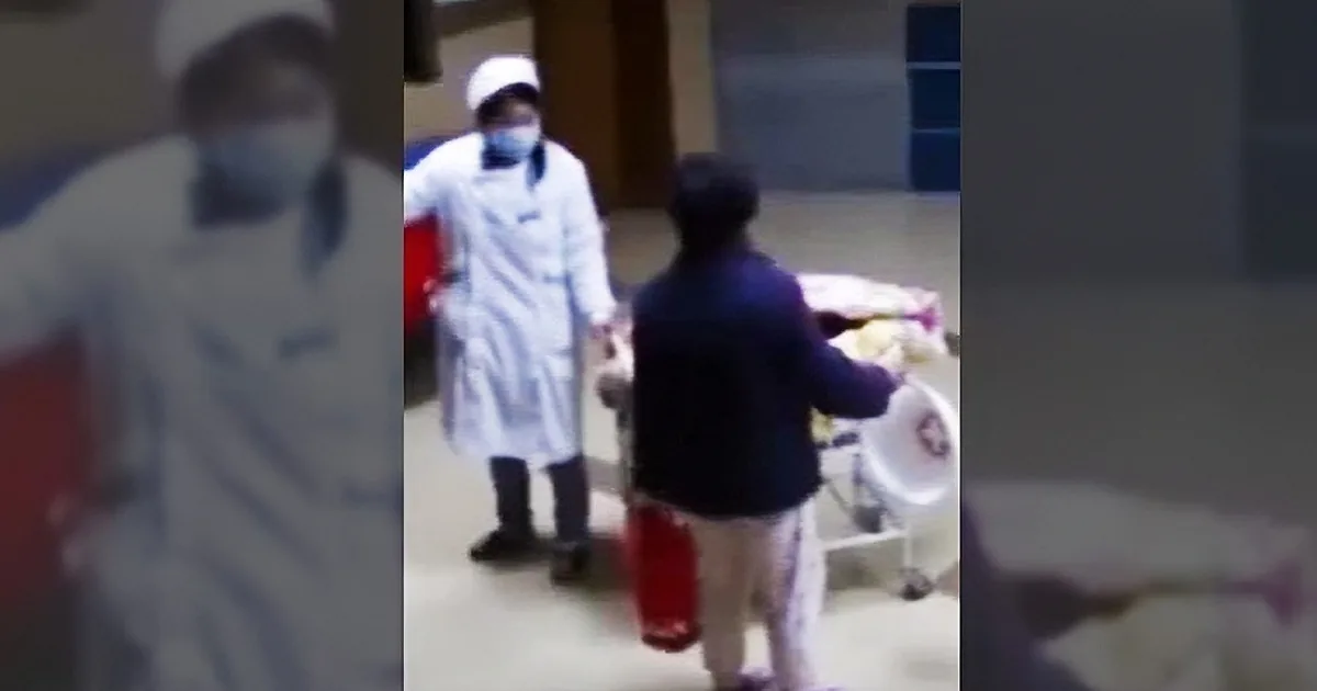 A person in a white uniform and mask is interacting with another individual in a dark jacket and cap.