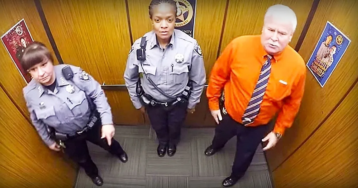 Three individuals in uniform and civilian attire stand in a hallway, one in orange shirt and tie, others in police uniforms.