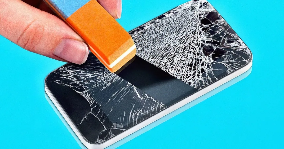 A hand holds an orange tool, applying it to a cracked smartphone screen.