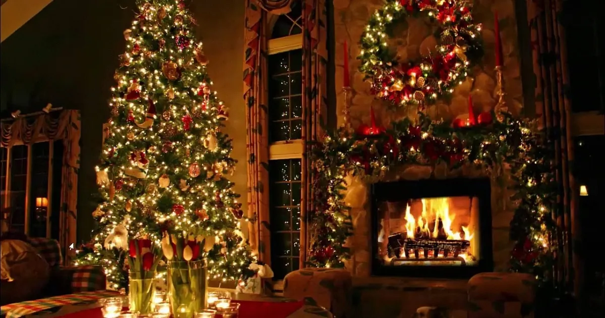 A beautifully decorated Christmas tree stands beside a cozy fireplace adorned with wreaths and lights.
