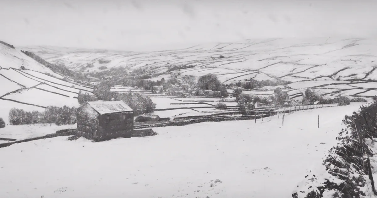 Snow-covered landscape with a barn, fields, and distant hills under a cloudy sky.