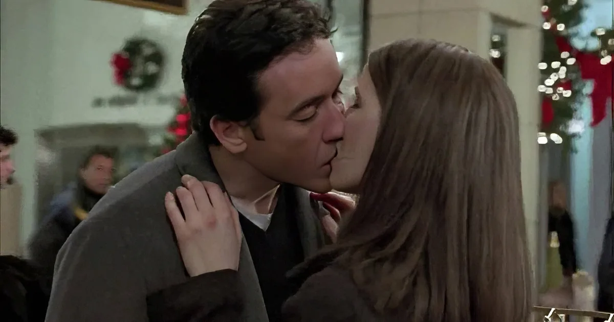 A man and woman share a passionate kiss in a festive, decorated setting.