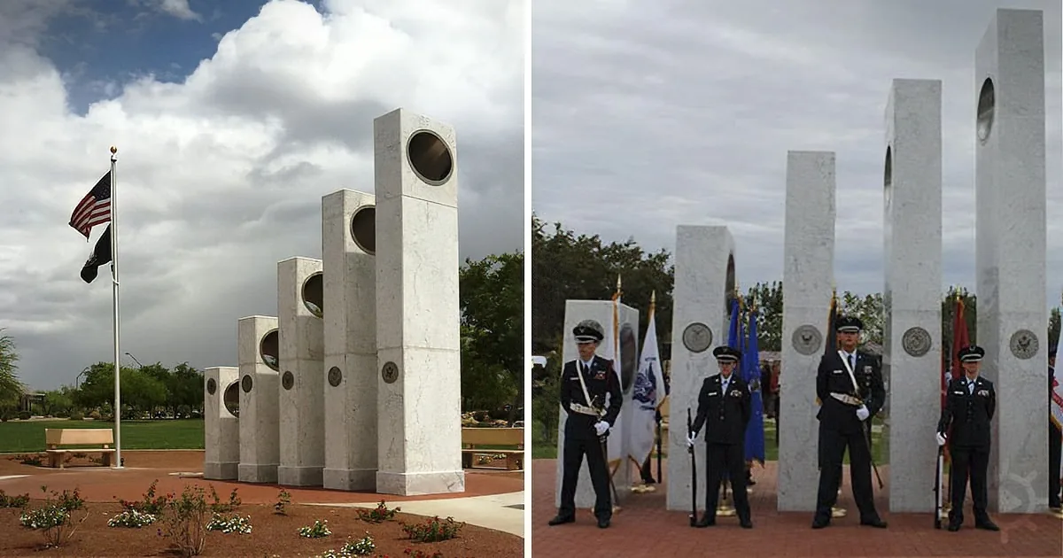 Monumental columns with circular cutouts, flags, and uniformed personnel stand under a cloudy sky.