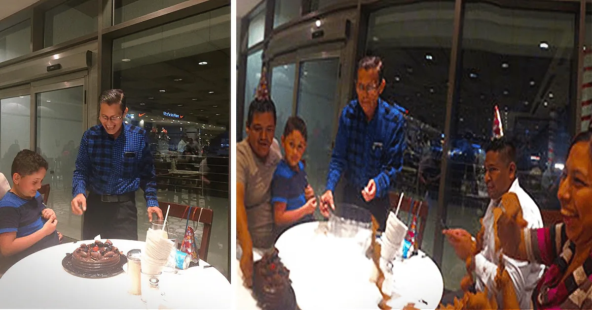 A man in a blue plaid shirt stands at a table with a chocolate cake, surrounded by smiling people in a celebratory setting.
