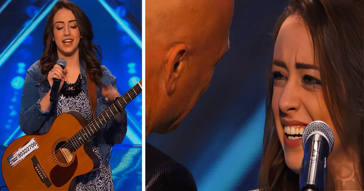 A woman sings passionately with a guitar, her expression filled with emotion, as she performs on stage.
