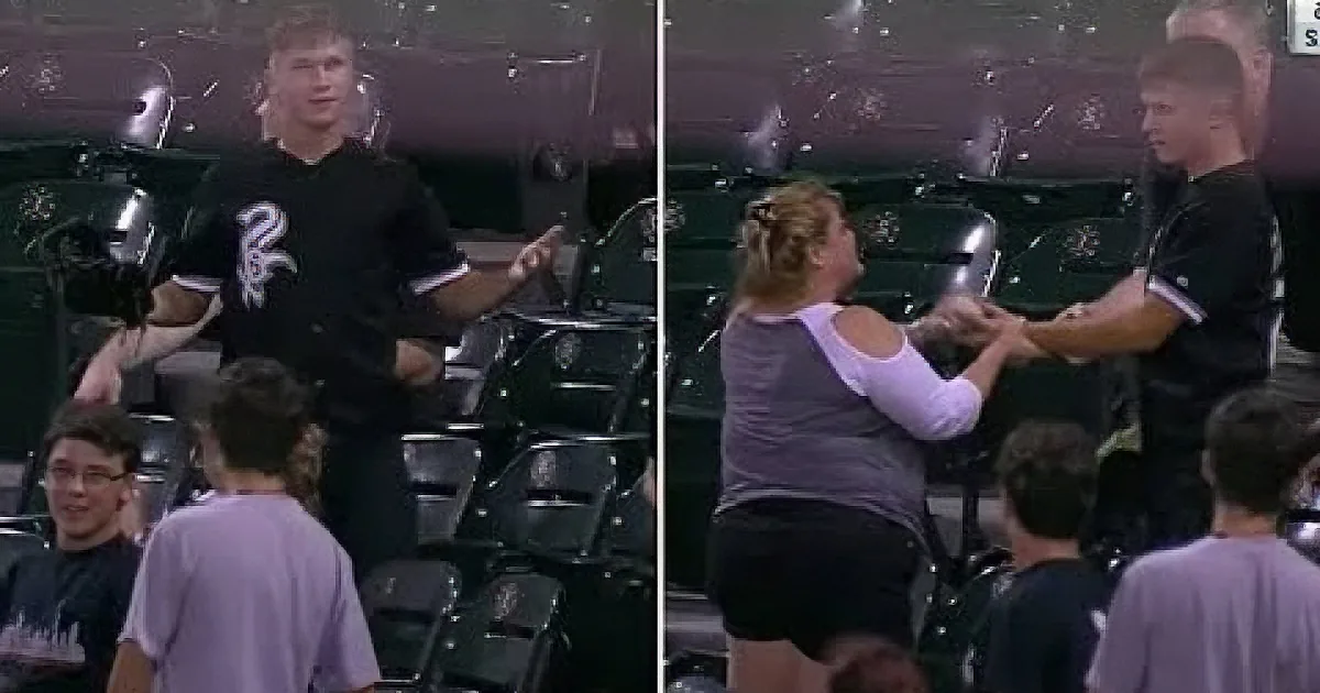 A man in a black shirt interacts with a woman in a purple shirt in a stadium setting.