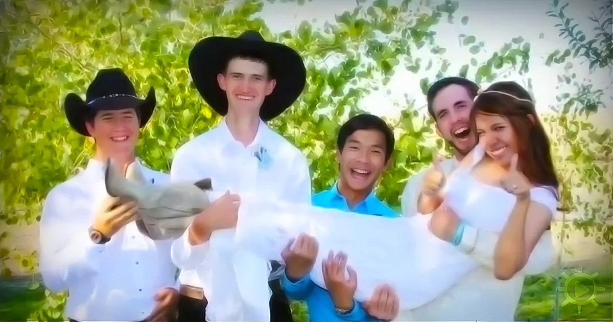 A group of five people, including two in cowboy hats, hold a white cloth together, smiling and giving thumbs up.