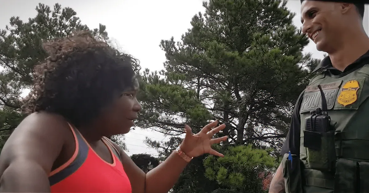 A woman in a red tank top gestures while talking to a police officer in uniform.