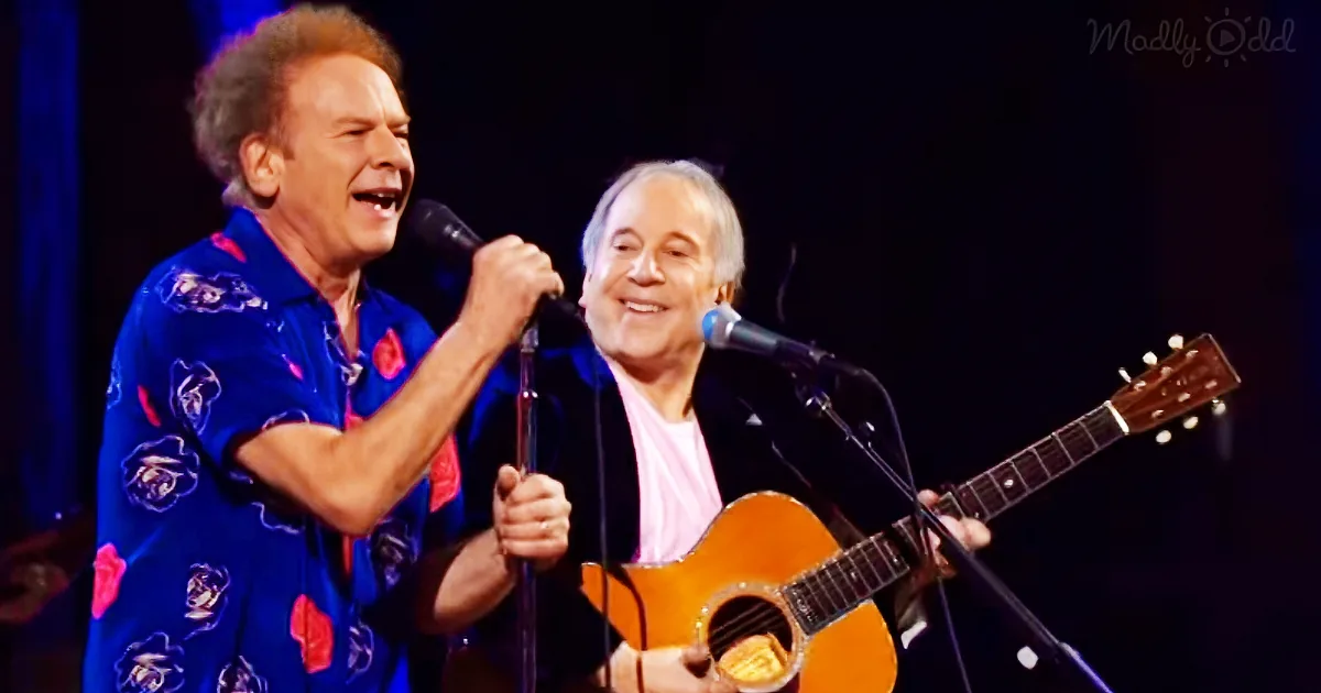 Two men are performing on stage, one singing into a microphone and the other playing guitar.