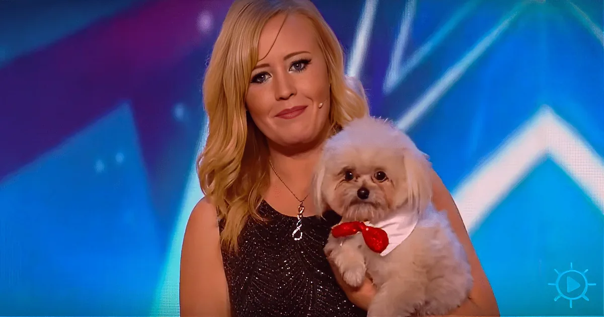 A woman with blonde hair holds a small white dog wearing a red bow tie.