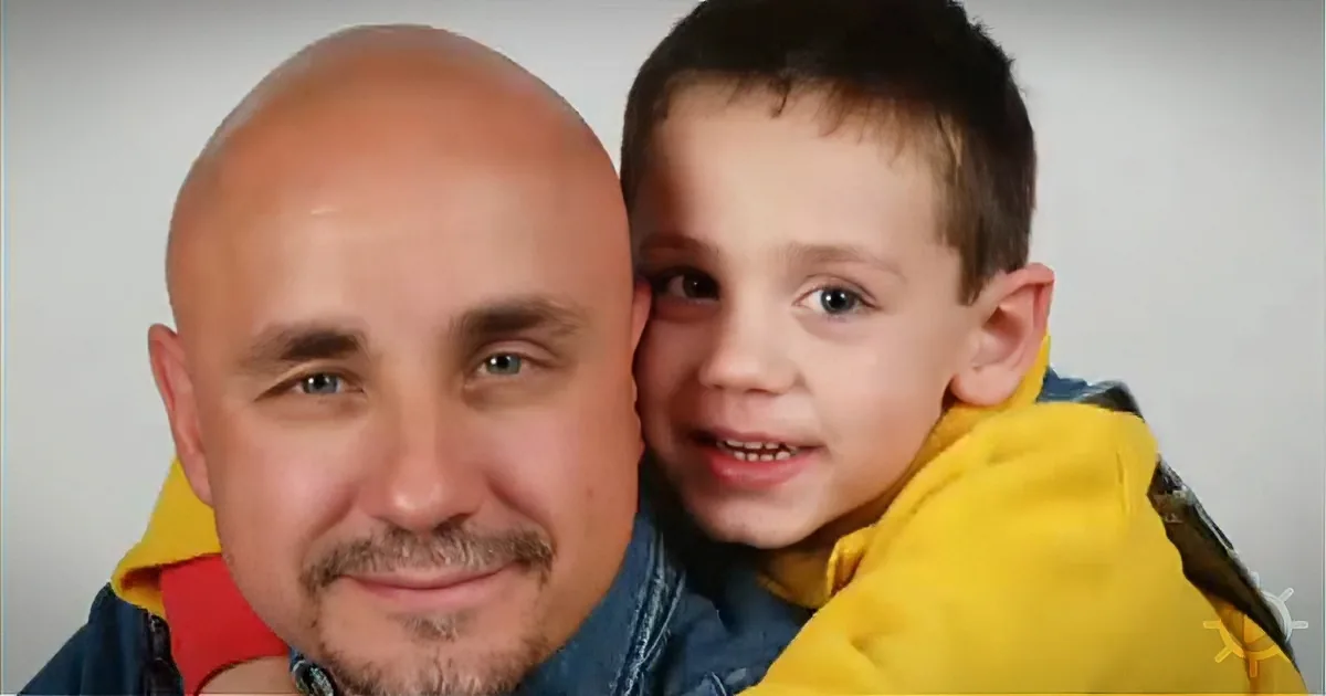 A man and a young boy, both smiling, are wearing jackets, with the boy leaning on the man's shoulder.