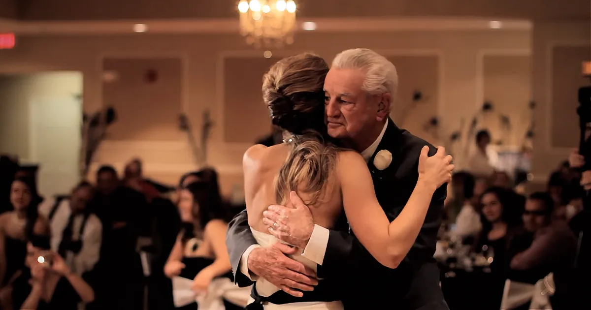 A bride and her father share a heartfelt embrace during a wedding reception.
