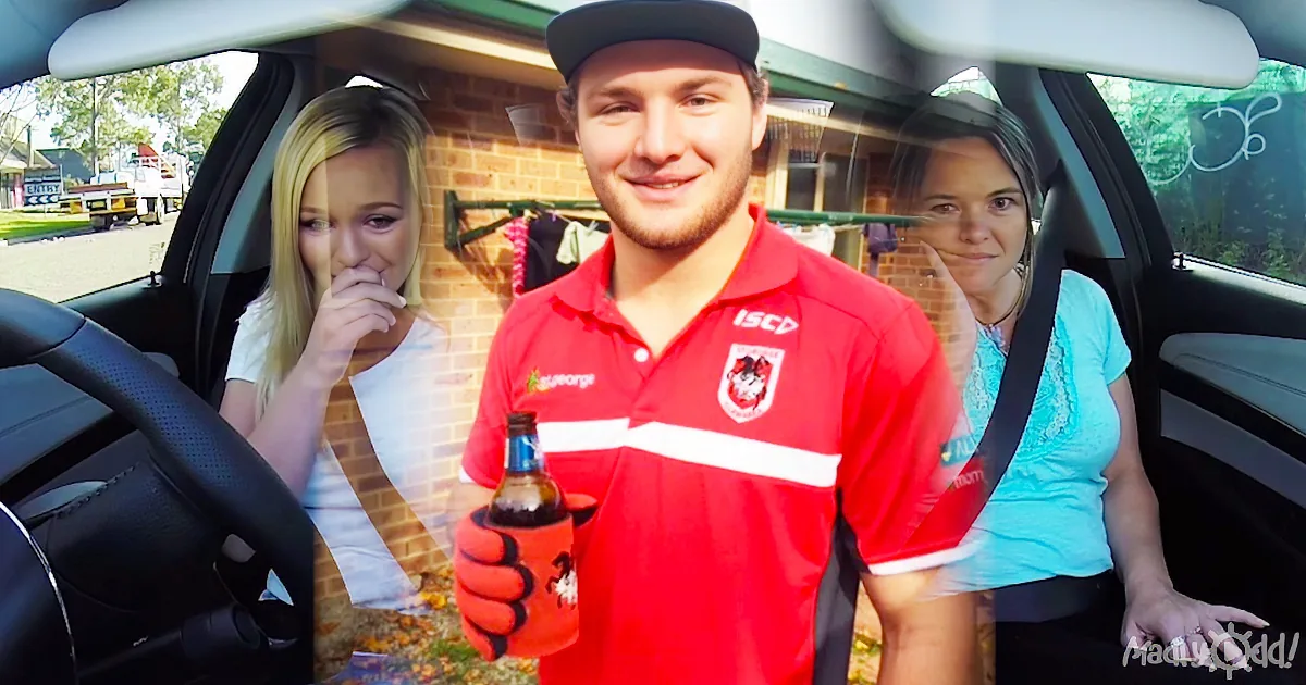 A man in a red sports jersey holds a drink, smiling, with two women in a car behind him.