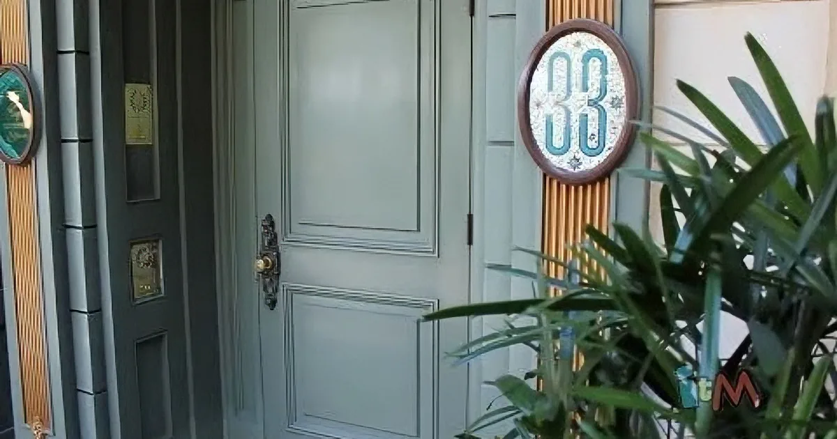A closed door with a golden handle and a round sign displaying "33" is the main subject.