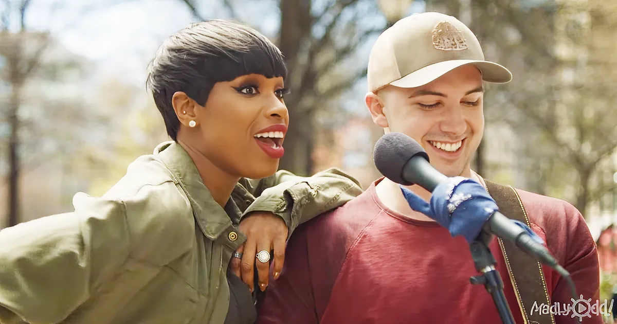 A woman in a green jacket leans on a man in a red shirt and cap, both smiling near a microphone.