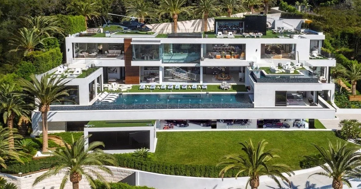 A luxurious modern villa with multiple levels, a pool, and a helicopter pad surrounded by palm trees.