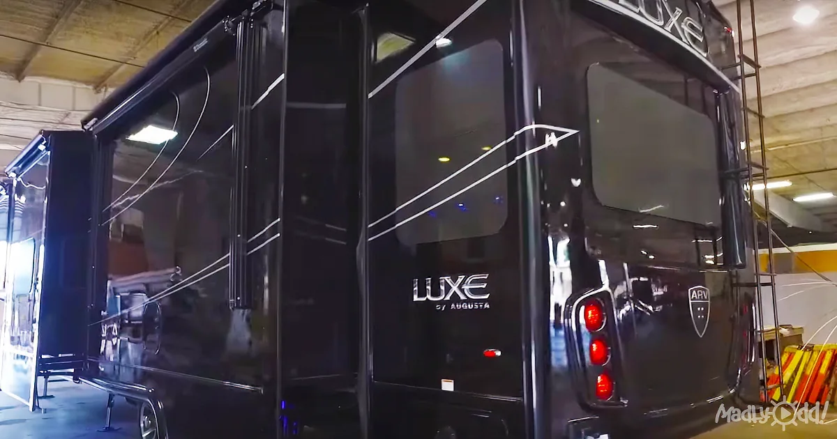 A sleek black Luxe by Augusta RV is displayed in a well-lit showroom with visible interior features and branding.