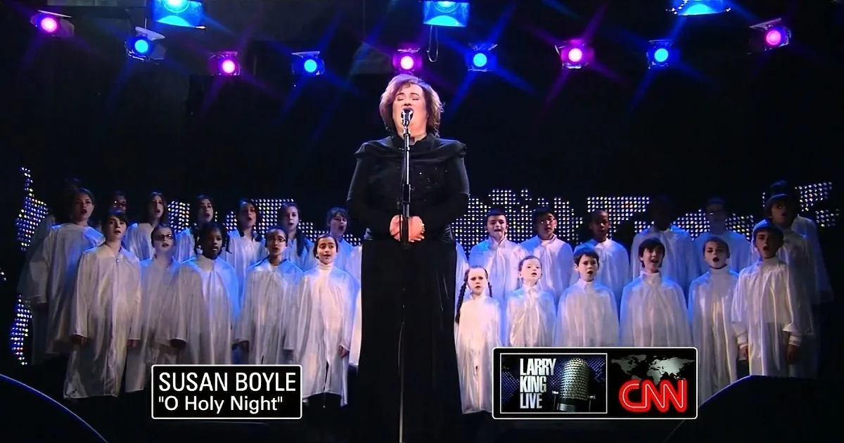 Susan Boyle sings "O Holy Night" on CNN with a choir behind her.