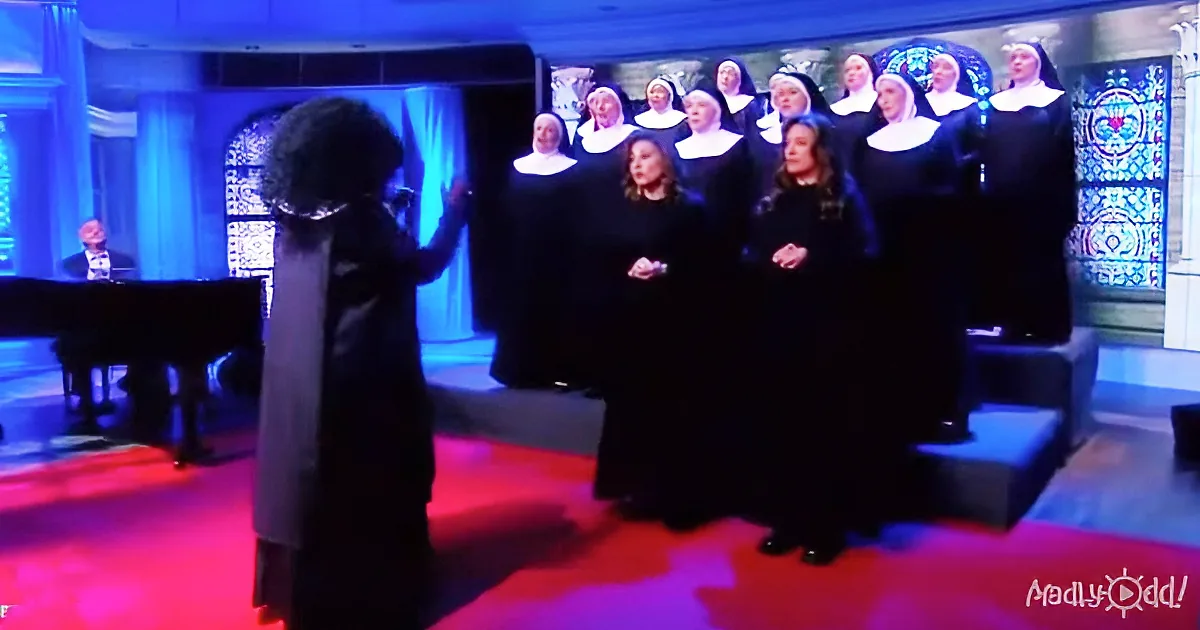 A conductor leads a choir in black robes with white collars, accompanied by a pianist in a dimly lit church setting.