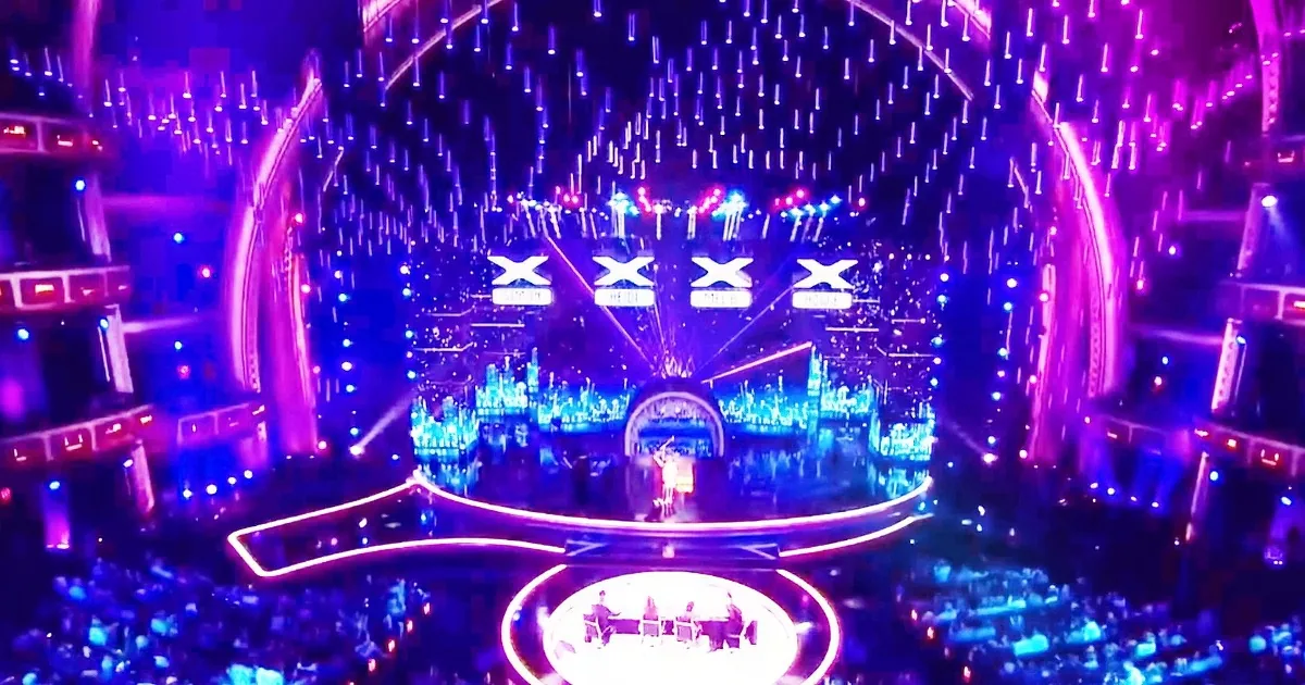 A vibrant concert stage with a cityscape backdrop, illuminated by colorful lights and surrounded by a cheering crowd.