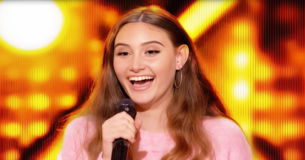 A person with long hair, wearing a pink top, holding a microphone against a vibrant, glowing background.