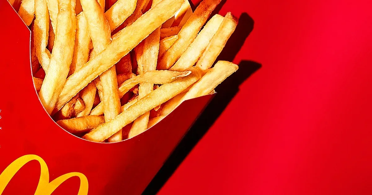 Golden McDonald's fries in a red box against a vibrant red background.