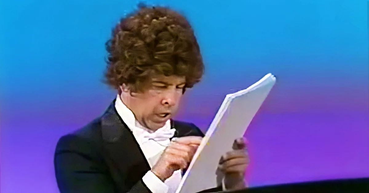 A man in formal attire is reading from a piece of paper.