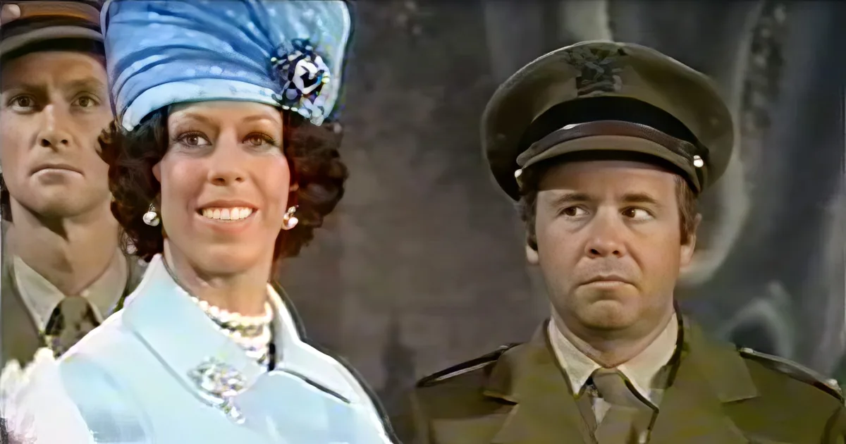 A woman in a blue uniform and hat smiles, flanked by two men in military uniforms.
