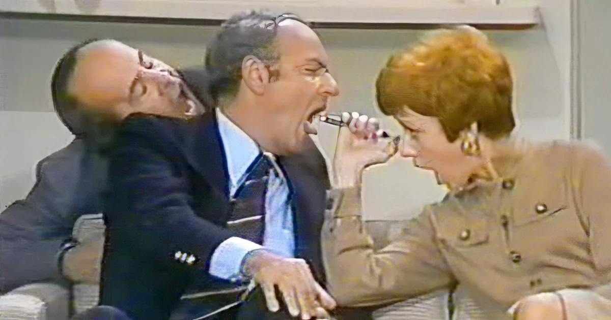 A man in a suit is being held back by a woman in a military-style jacket.