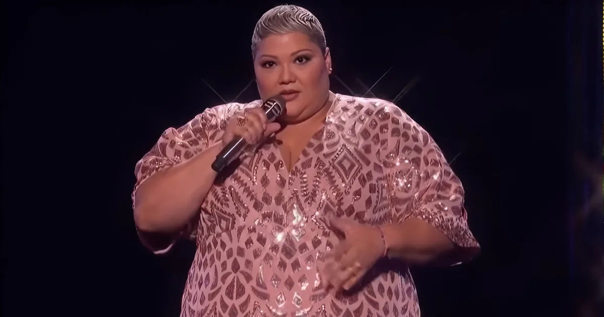 A woman in a sparkly pink dress sings into a microphone on stage.