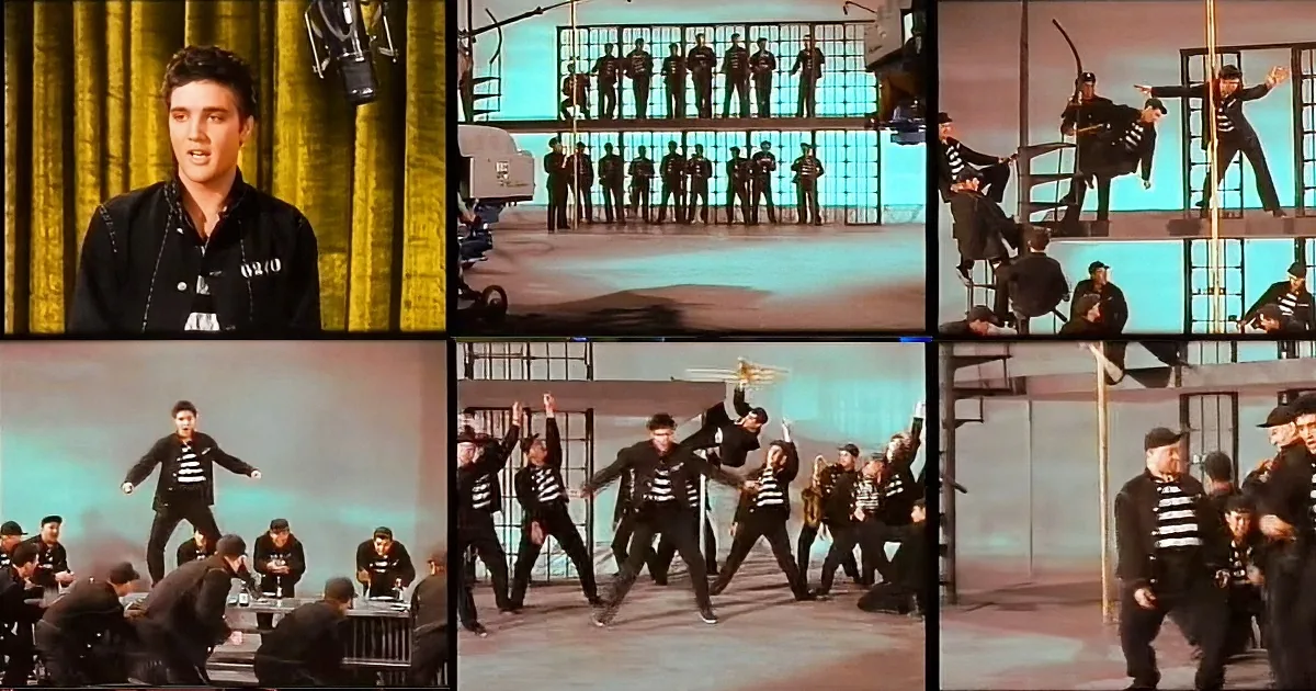 Elvis Presley in a black outfit, surrounded by dancers in striped prison uniforms, performing on stage.
